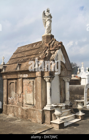 Un angelo statua si trova sulla cima di una tomba nel cimitero di Lafayette #2 nel Garden District di New Orleans, Louisiana Foto Stock