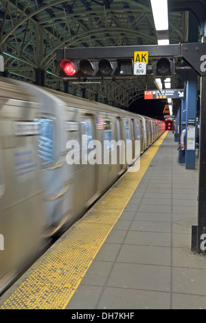 Un treno della metropolitana in movimento come si arriva a Stillwell Avenue Station in notturna a Coney Island, Brooklyn Foto Stock