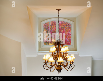 Foto del lampadario a soffitto, costituito da una dozzina di piccole lampade, con una grande finestra che visualizza l'autunno alberi in colori vibranti Foto Stock