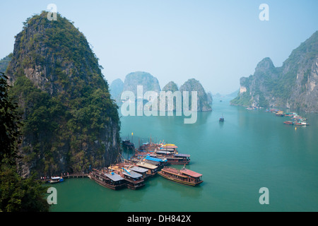 Una vista del calcaree spettacolari formazioni carsiche che si eleva al di sopra di barche ormeggiate nella baia di Halong, Vietnam. Foto Stock
