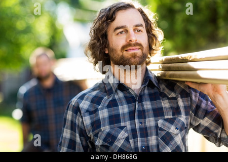 Carpenter assi portanti mentre guarda lontano Foto Stock