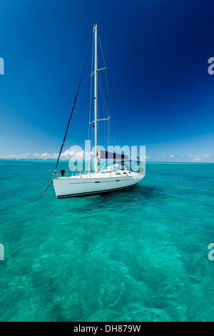 Barca a vela bianca galleggia sul chiaro blu turchesi acque dei Caraibi come se sospeso su trasparente ripiano in vetro Foto Stock