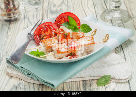 Spiedini di Turchia sul riso con salsa di pomodoro e pomodori grigliati Foto Stock