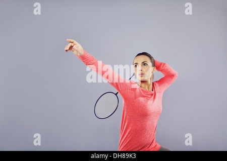 Bella giovane femmina la riproduzione di badminton su sfondo grigio. Attraente donna caucasica badminton player con un sacco di copyspace. Foto Stock