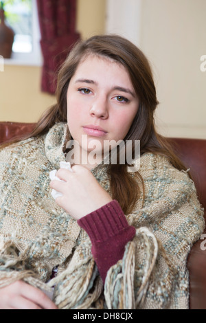 Cattiva ragazza adolescente seduto sul divano avvolto in una coperta Foto Stock