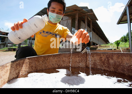 Gli agricoltori di Bago durante un focolaio di influenza aviaria o H5N1, la pulizia e la disinfezione delle attrezzature; Yangon, Birmania Foto Stock