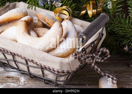 Lo zucchero in casa cookie crescent servita nel cesto vicino albero di natale sopra il vecchio tavolo in legno Foto Stock