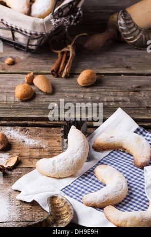 Lo zucchero in casa cookie crescent servita con accessori vintage, mandorle e spezie su un vecchio tavolo in legno Foto Stock