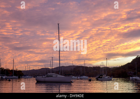 Un incredibile tramonto colorato scena su Windermere nel Lake District. bella arancione e rosa di colori tra le nuvole. Foto Stock