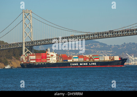 Un Yang Ming Line nave container passa sotto il San Francisco-Oakland Bay Bridge di San Francisco, California, Stati Uniti d'America. Foto Stock