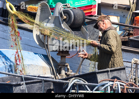 Vecchio Pescatore esaminando e riassettavano le reti. Warnemunde Rostock Germania Foto Stock
