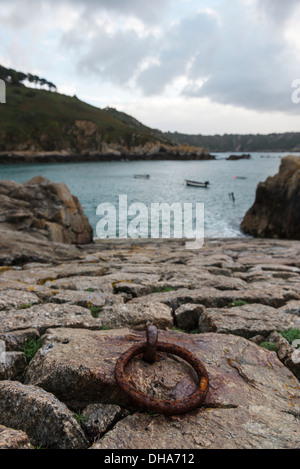 Di ferro arrugginito anello di ormeggio sulla pietra di uno scalo All Saints Bay Harbor, Guernsey, Isole del Canale. Foto Stock