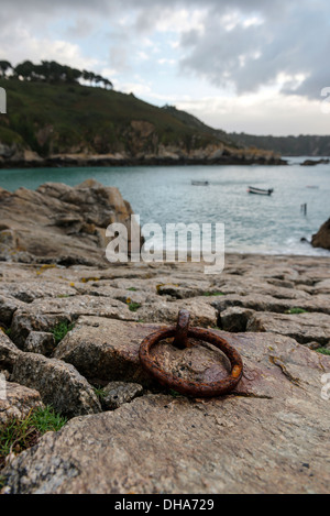 Di ferro arrugginito anello di ormeggio sulla pietra di uno scalo All Saints Bay Harbor, Guernsey, Isole del Canale. Foto Stock