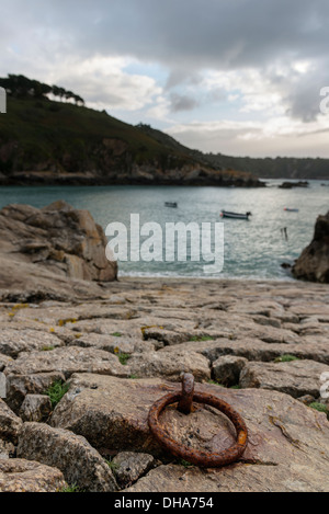 Di ferro arrugginito anello di ormeggio sulla pietra di uno scalo All Saints Bay Harbor, Guernsey, Isole del Canale. Foto Stock