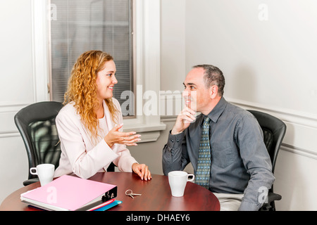 Femmina di agente immobiliare a parlare al nuovo proprietario di casa in office sala riunioni Foto Stock