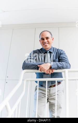 Ritratto di felice orgoglioso business man standing in office corridoio appoggiata sul parapetto Foto Stock