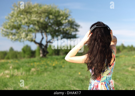 Giovane donna con le cuffie per ascoltare musica sul campo Foto Stock