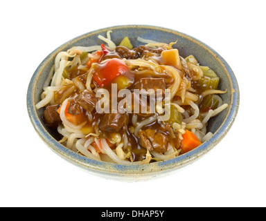 Una grande dose di oriental tagliatelle e verdure CON MANZO bocconcini e salsa in una vecchia ciotola grigio su uno sfondo bianco. Foto Stock