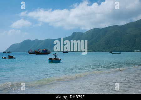 Un pescatore appena fuori dalla riva di una spiaggia Hai su Con figlio Isola, uno dei Con Dao isole, Vietnam. Foto Stock