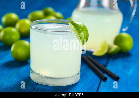 Preparato di fresco limonata fresca fuori del limes con cubetti di ghiaccio nel bicchiere guarnito con una fetta di lime Foto Stock