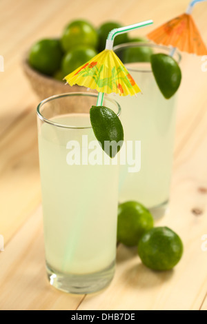 Preparato di fresco limonata fresca fuori del limes in bicchiere guarnito con uno spicchio di lime e ombrellino di carta Foto Stock