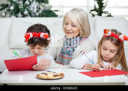 Donna senior con i fratelli e le sorelle a scrivere lettere a Babbo Natale Foto Stock