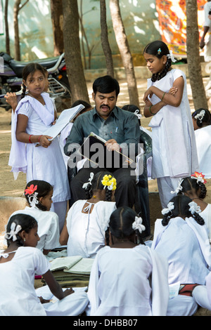 Rurale villaggio indiano di alta scuola ragazze aventi lavoro segnato dalla loro insegnante in una classe esterna. Andhra Pradesh, India Foto Stock