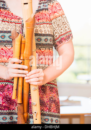 Primo piano della donna che mantiene una varietà di flauti in legno Foto Stock