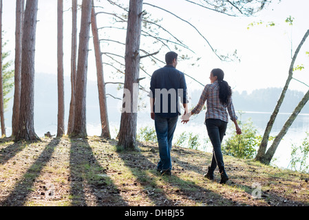 Lakeside. Un paio di camminare all'ombra di alberi di pino in estate. Foto Stock