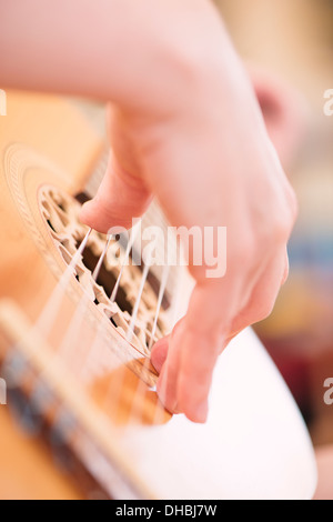 Primo piano della mano womans giocando su legno chitarra acustica Foto Stock