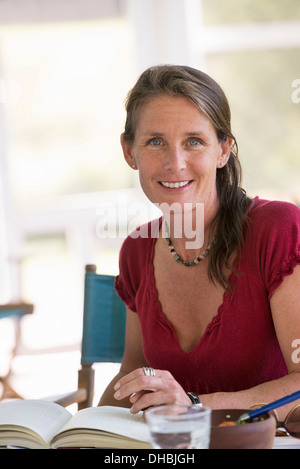 Una donna la lettura di un libro, seduti ad un tavolo. Foto Stock