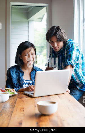 Un uomo e una donna che utilizza un computer portatile in un cafe'. Foto Stock