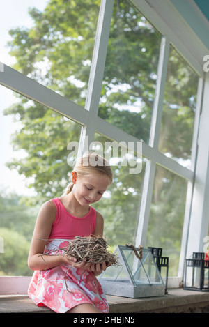 Una giovane ragazza in una cucina che indossa un abito rosa. Tenendo un nido. Foto Stock