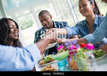 Un gruppo di uomini e donne intorno ad un tavolo per la condivisione di un pasto in un agriturismo cucina. Foto Stock