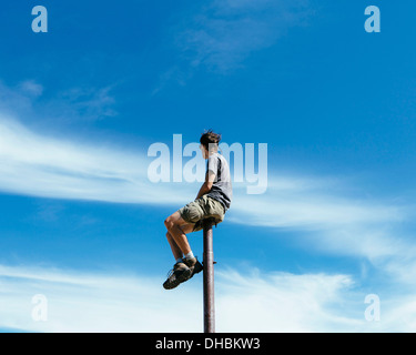 Uomo seduto in equilibrio su parte superiore montante metallico a guardare verso il cielo espansiva su sorpresa Alpine Lakes Wilderness mt Foto Stock