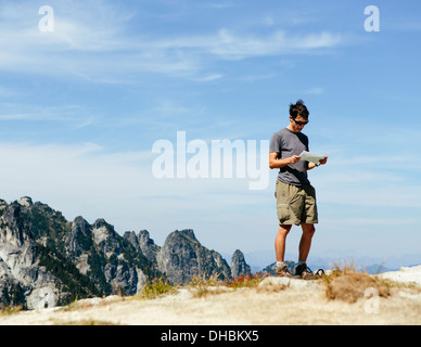 Un escursionista sul vertice di montagna guardando alla mappa. Sorpresa Alpine Lakes Wilderness a Mount Baker-Snoqualmie foresta nazionale, Foto Stock