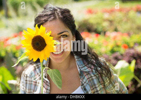 Una fattoria la coltivazione e vendita di ortaggi e frutta. Donna che mantiene un grande girasole. Foto Stock