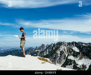 Un escursionista sul vertice di montagna guardando alla mappa. Sorpresa Alpine Lakes Wilderness a Mount Baker-Snoqualmie foresta nazionale, Foto Stock