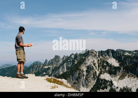 Un escursionista sul vertice di montagna guardando alla mappa. Sorpresa Alpine Lakes Wilderness a Mount Baker-Snoqualmie foresta nazionale, Foto Stock