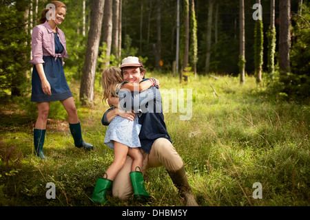 Un uomo che abbraccia un bambino. Una famiglia in un bosco a piedi. Foto Stock