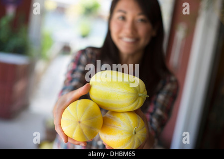 Una fattoria la coltivazione e vendita di ortaggi e frutta. Una donna che mantiene fresco raccolte spremute a strisce. Foto Stock