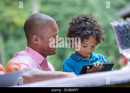 Un picnic sull'azienda. Fresca frutta organica sul tavolo. Un padre e figlio seduti insieme. Foto Stock