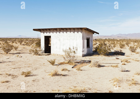 Un piccolo edificio abbandonato nel deserto di Mojave paesaggio. Foto Stock