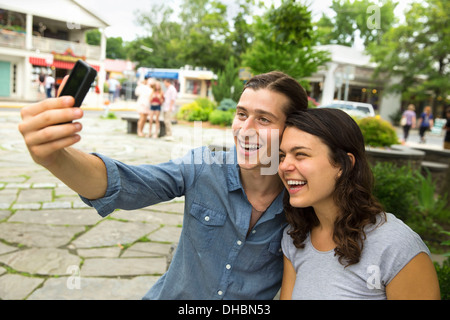 Una giovane coppia affiancati, flirtare e scattare fotografie. Foto Stock