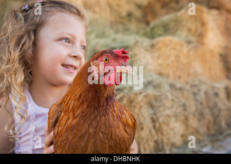 Una giovane ragazza con un pollo in un pollaio. Foto Stock