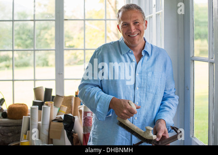 Un uomo in un workshop, tenendo un falegname la fascetta nella sua mano. Foto Stock