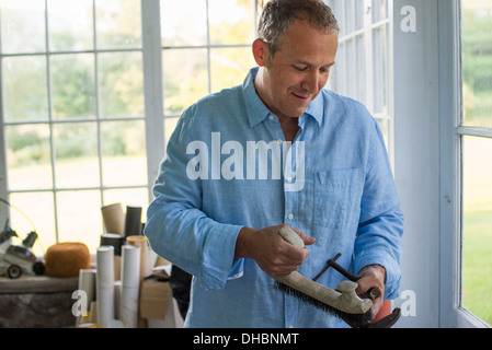 Un uomo in un workshop, tenendo un falegname la fascetta nella sua mano. Foto Stock