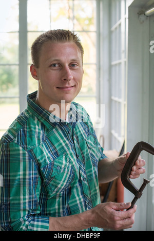 Un uomo in un workshop, tenendo un falegname la fascetta nella sua mano. Foto Stock