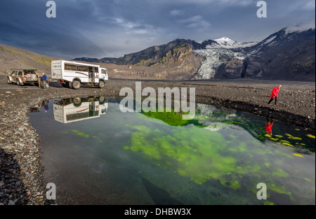 Donna escursionismo da un laghetto con alghe e cenere, Gigjokull ghiacciaio, Icealnd Foto Stock