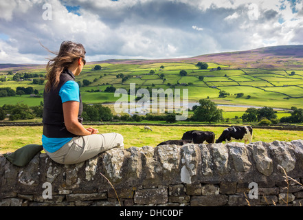 Escursionista femmina seduti sulla parete vicino al villaggio di Reeth nel Yorkshire Dales National Park, England, Regno Unito Foto Stock